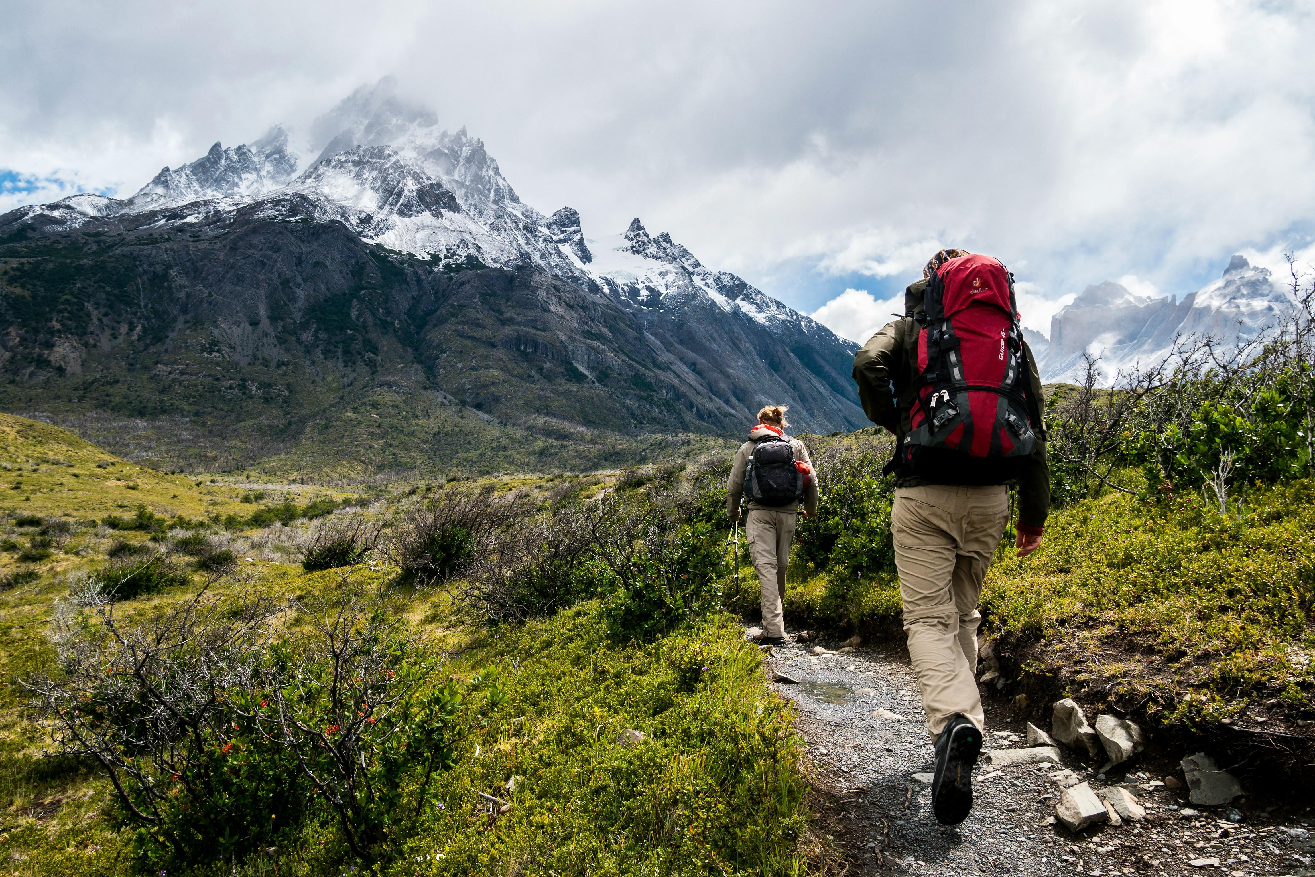 Hikers on a mountain trail with snow-capped peaks